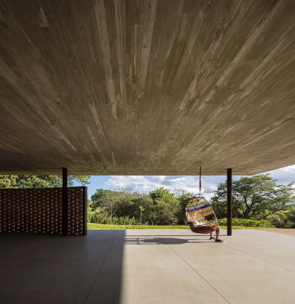 Hamaca bajo el techo de hormigón encofrado y vista del jardín desde el porche de la Casa plana de MK27
