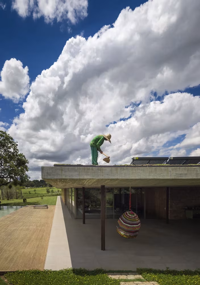 Operario sobre la cubierta de la Casa plana de MK27 con paneles solares y hamaca bajo el voladizo