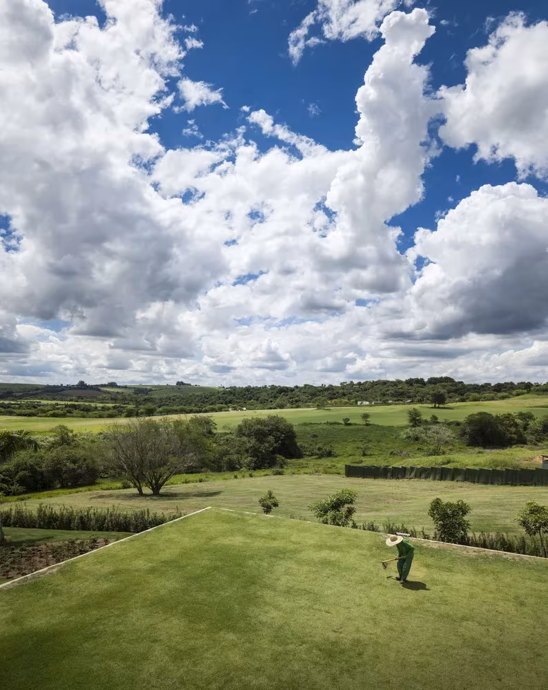 Cubierta ajardinada de la Casa plana de MK27 con vistas al campo de Porto Feliz bajo un cielo de nubes
