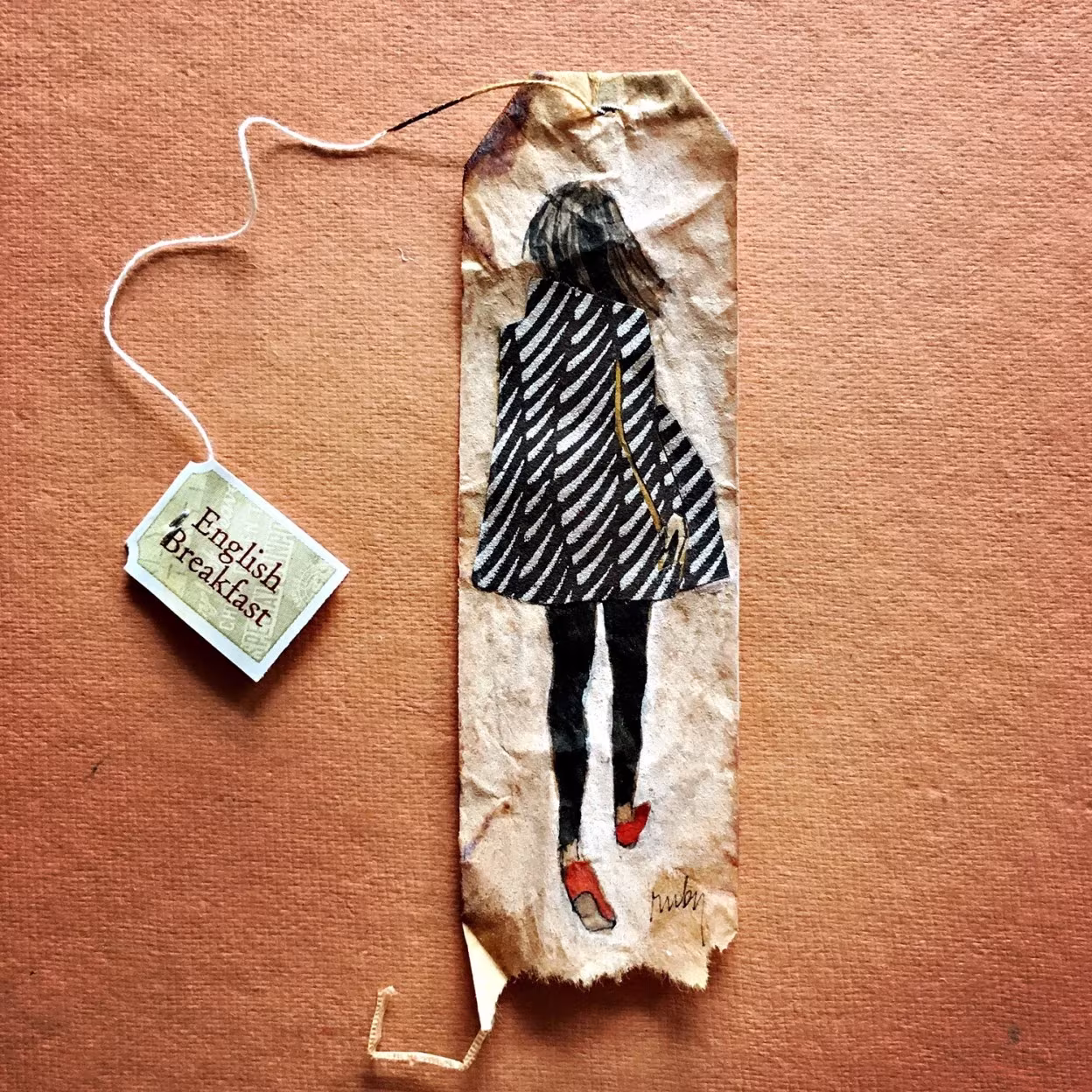 Bolsita de té alargada de Ruby Silvious con una figura de espaldas con abrigo de rayas blancas y negras