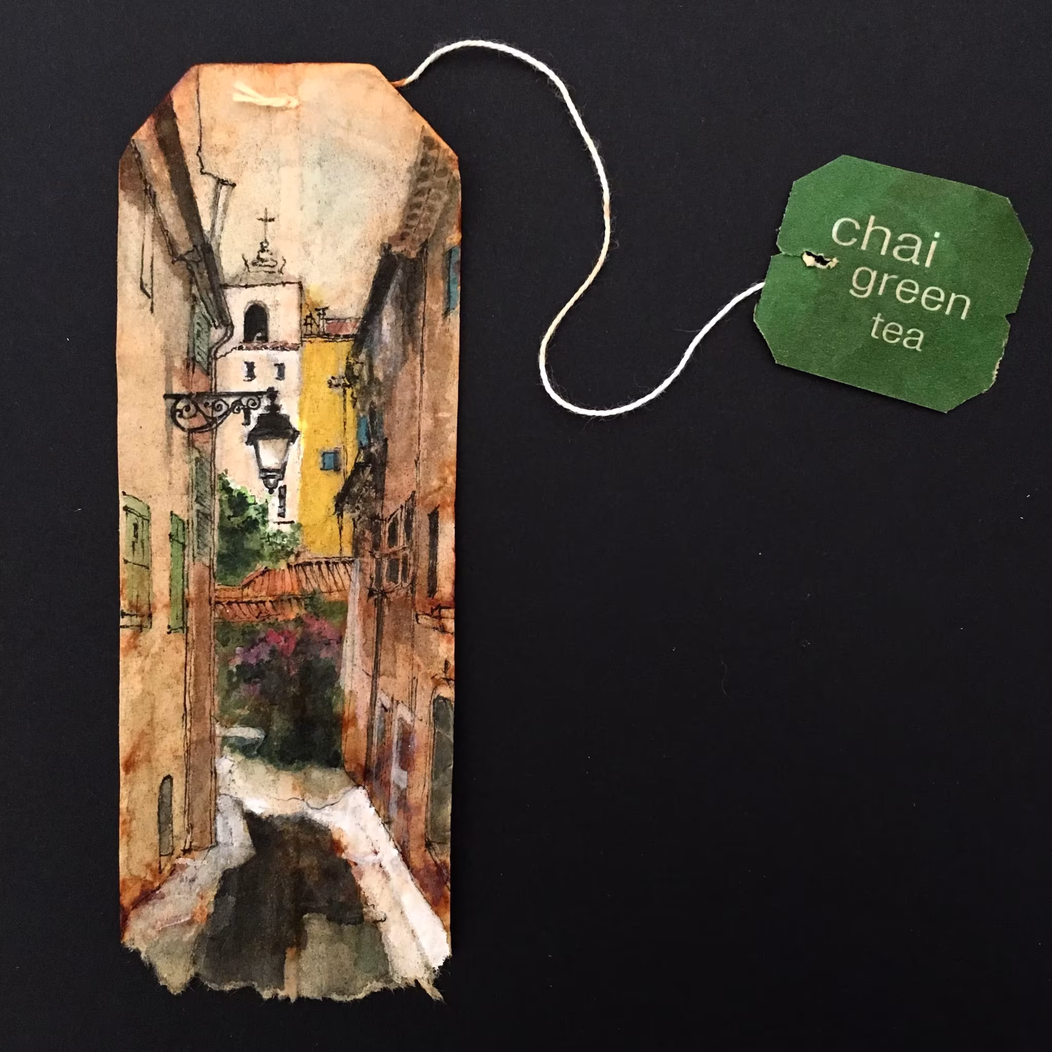 Bolsita de té de Ruby Silvious con una estrecha calle europea pintada en acuarela y un campanario