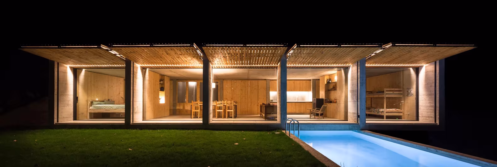 Casa Retina de Arnau estudi de noche, con salones iluminados abiertos a la piscina y el césped, Santa Pau