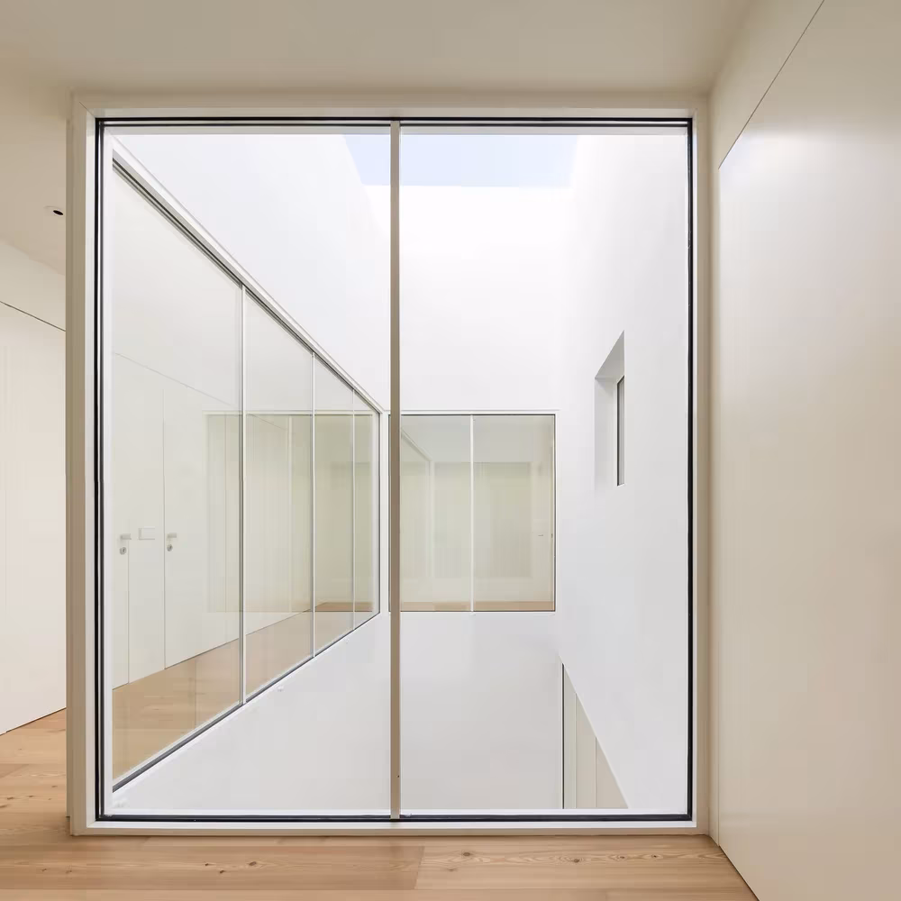 Gran puerta de vidrio corredera que se abre al patio interior de la Casa Brotero de phdd arquitectos