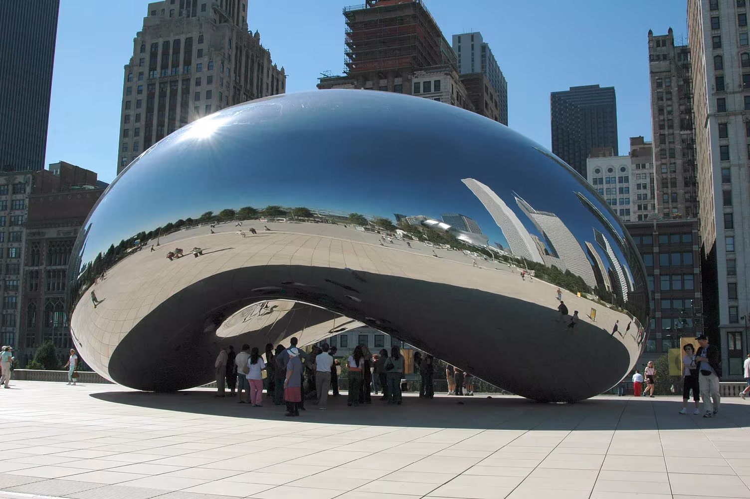 Escultura Cloud Gate de Anish Kapoor en Chicago, superficie de acero pulido que refleja rascacielos y visitantes