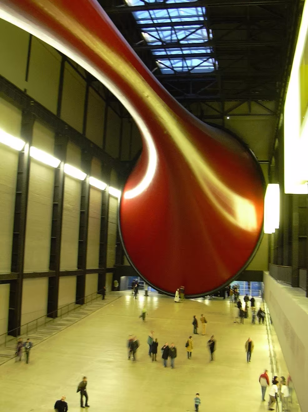Visitantes bajo la enorme membrana roja de Marsyas de Anish Kapoor suspendida en la Sala de Turbinas