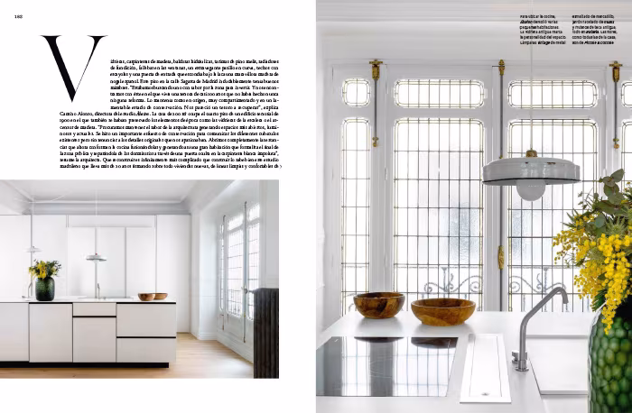 Doble página de AD España con la cocina blanca y una ventana de carpintería metálica con bol de madera en el fregadero