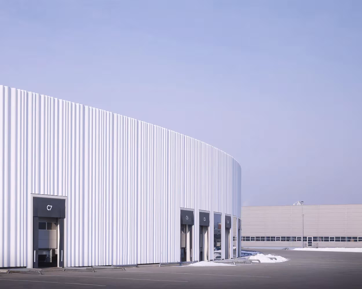 Muro curvo blanco con muelles de carga del pabellón circular de SANAA en el Vitra Campus