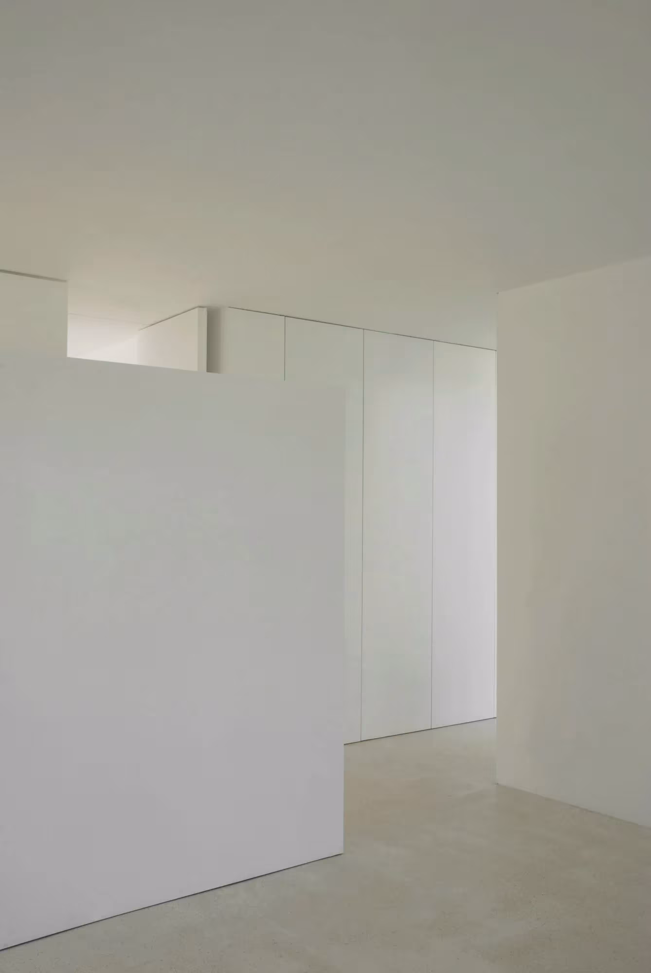 Interior blanco con tabique exento y armario empotrado en una vivienda de Aires Mateus en Bom Sucesso