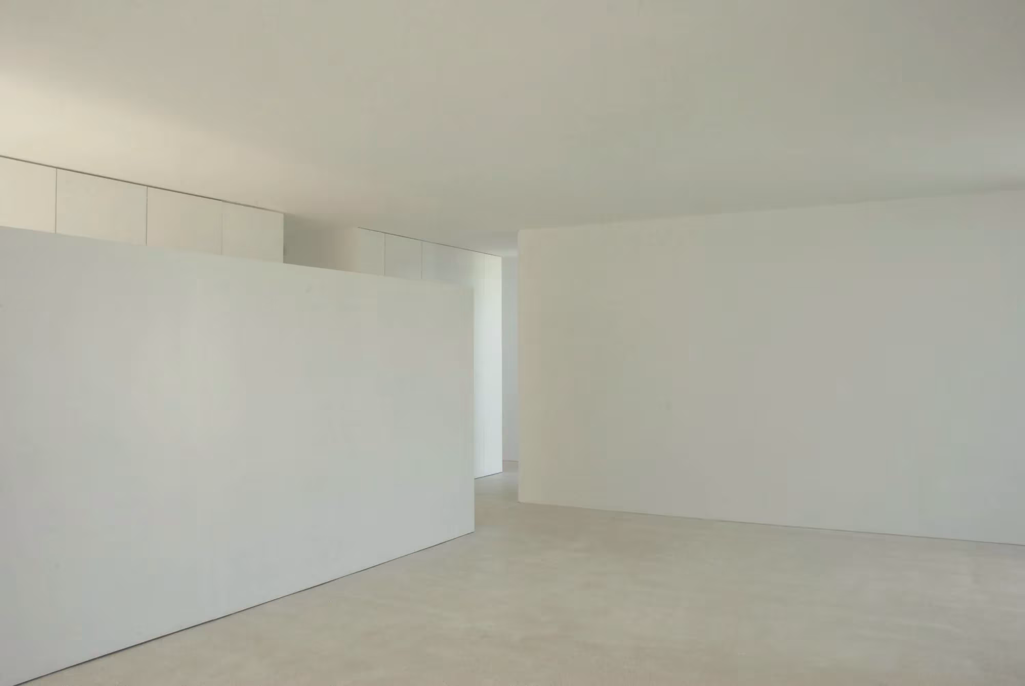 Sala blanca con tabique exento y suelo claro en una vivienda de Quinta do Bom Sucesso, de Aires Mateus