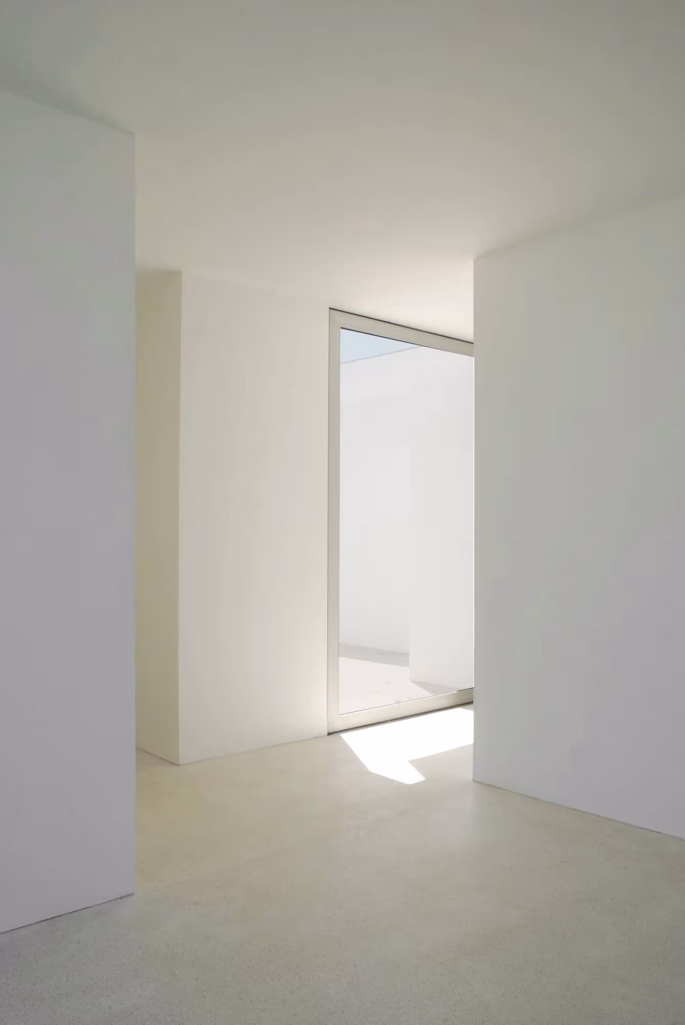 Estancia blanca con ventana en esquina y luz rasante en las casas de Aires Mateus en Quinta do Bom Sucesso