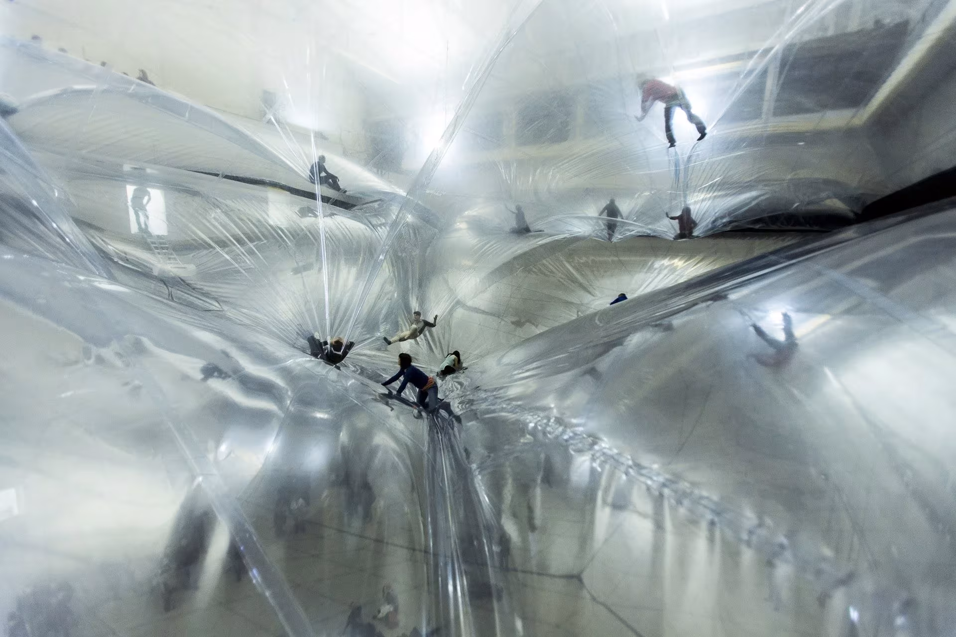 Personas tumbadas sobre las membranas transparentes de On Space Time Foam de Tomás Saraceno