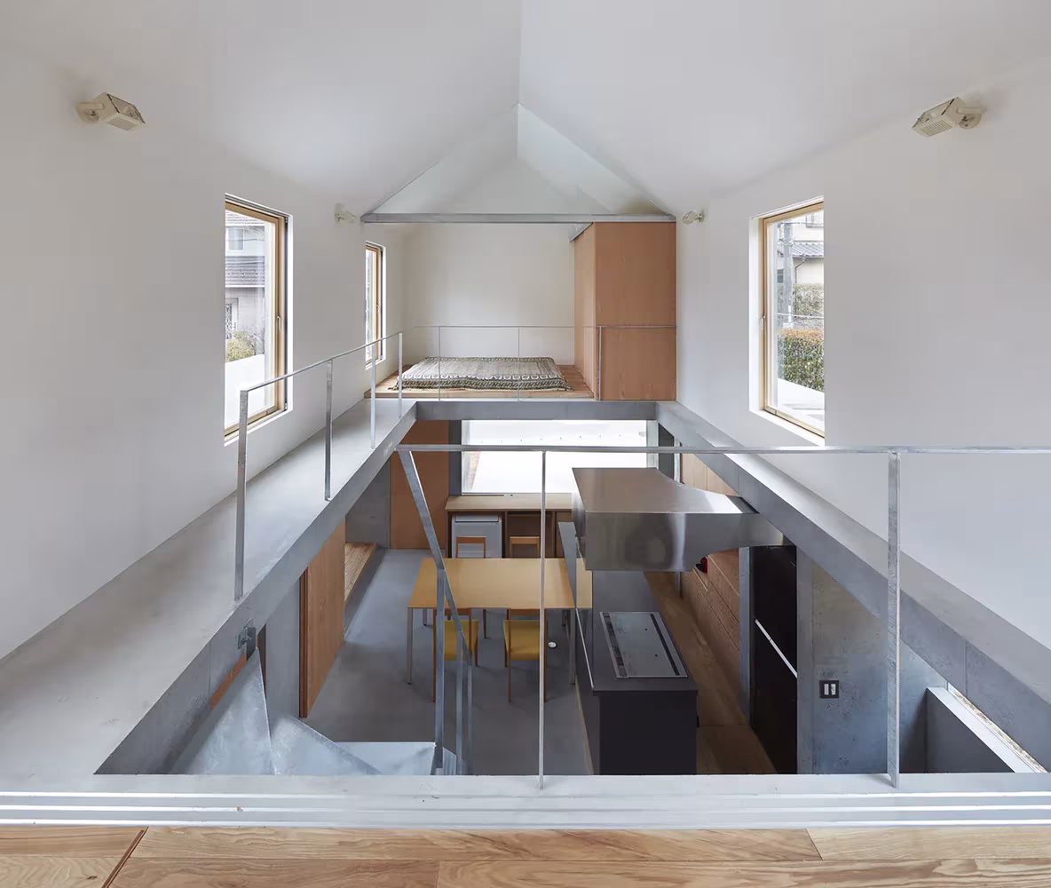 Vista cenital desde la entreplanta hacia el comedor y la cocina bajo la cubierta a dos aguas de la casa de Tomohiro Hata