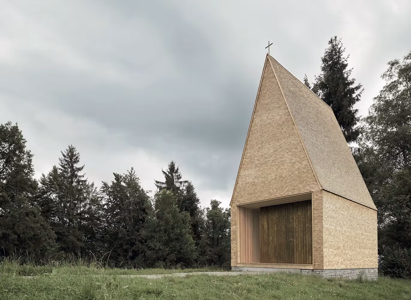 Capilla Salgenreute de tejuelas de madera con cruz entre abetos, vista frontal, de Bernardo Bader en Krumbach