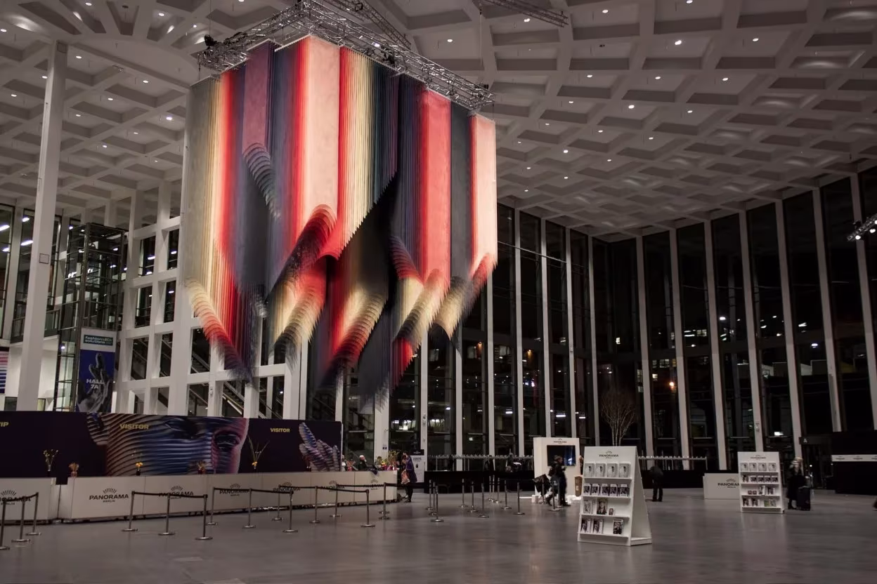 Instalación Flickering Lights de Quintessenz, telas de colores suspendidas en un gran vestíbulo acristalado en Berlín