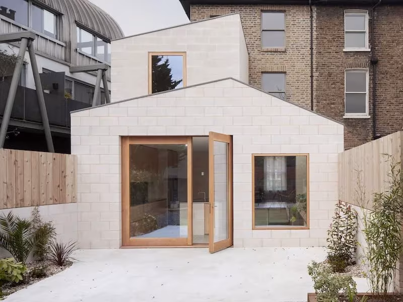 Ampliación de Al-Jawad Pike en una casa victoriana de Peckham, volumen claro con puerta de madera ante un patio