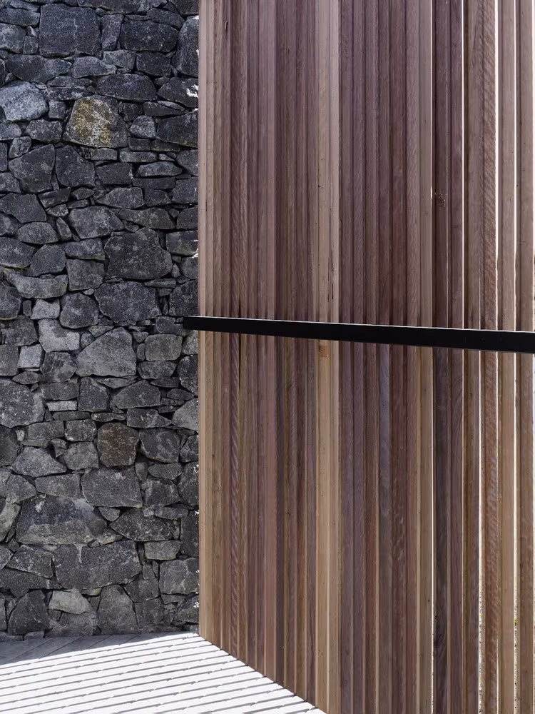 Detalle del muro de dolerita y las lamas verticales de madera en D'Entrecasteaux House, de Room11 Architects