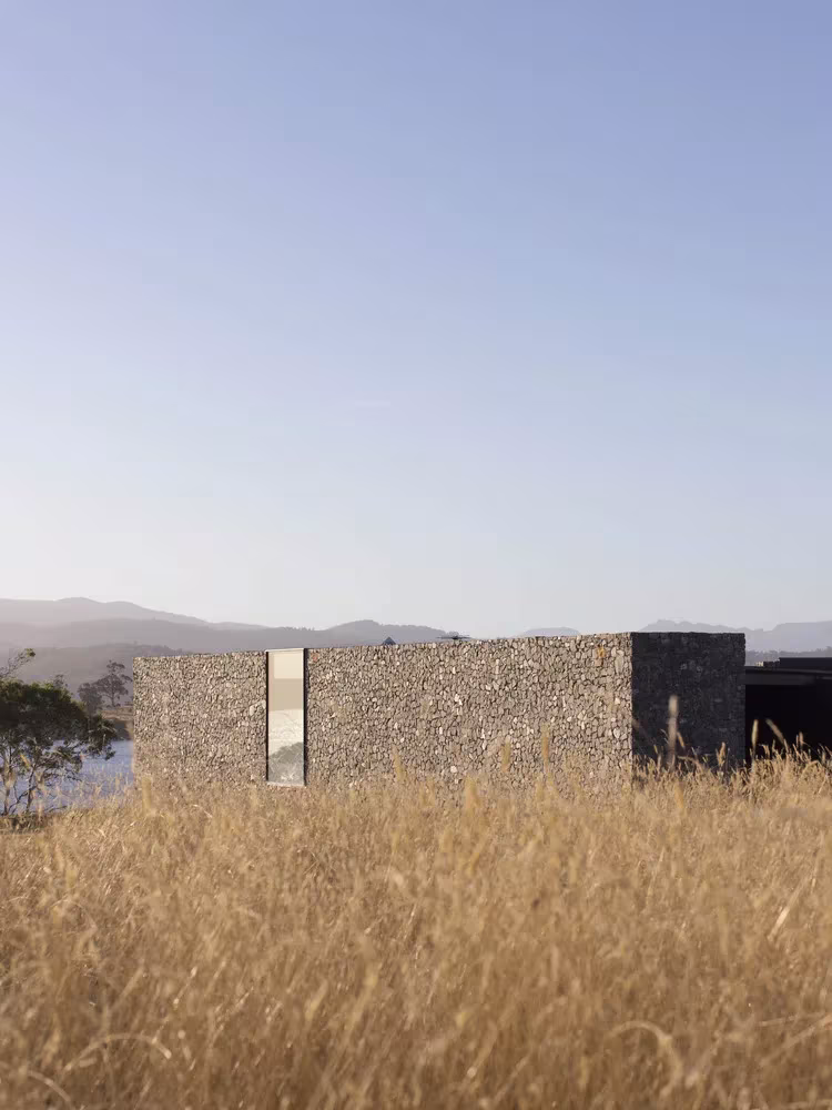 Testero de dolerita con una ventana estrecha entre hierbas altas en D'Entrecasteaux House, de Room11