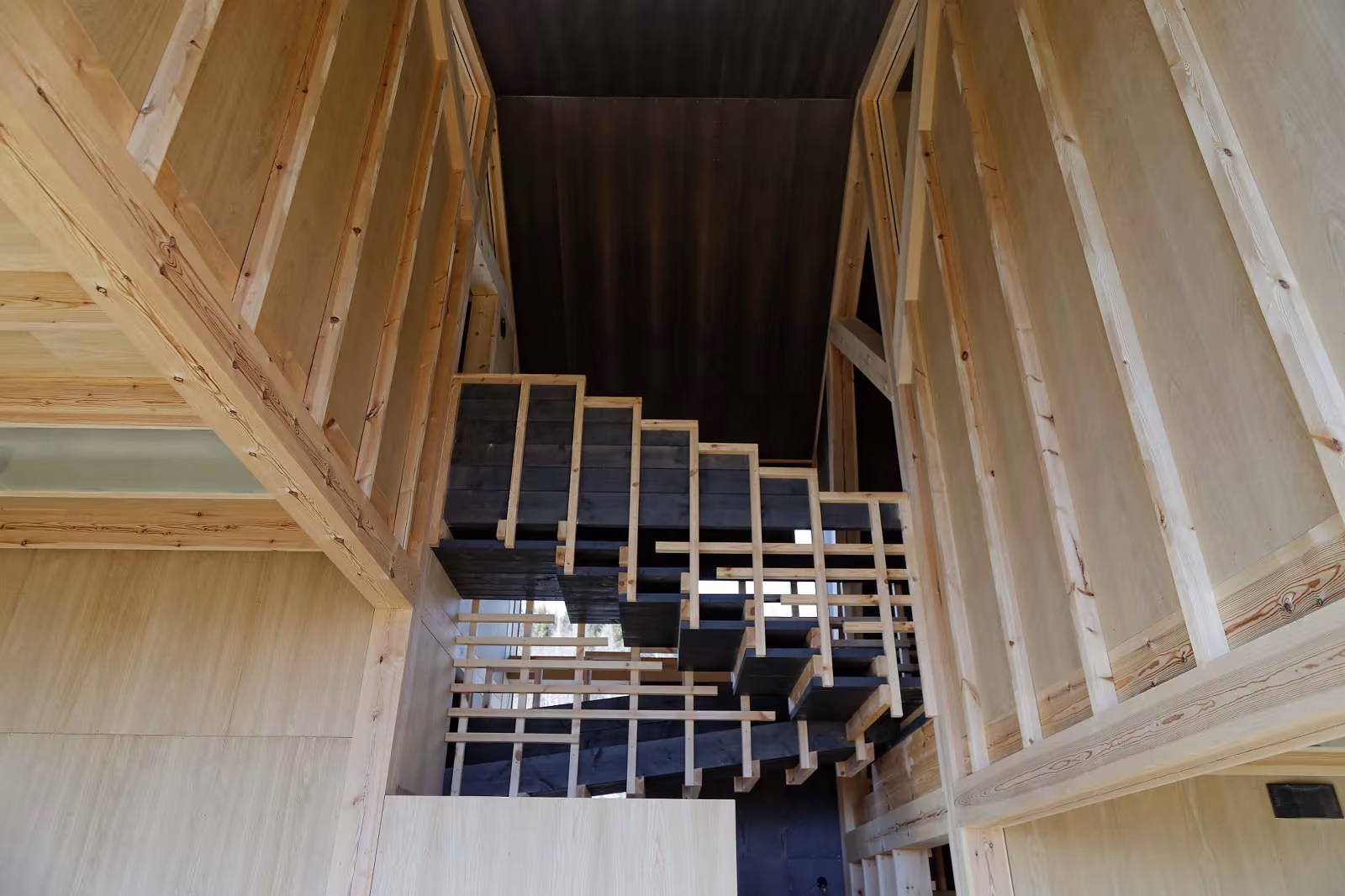 Escalera de madera entre paredes inclinadas de entramado a la vista en la Villa Gudbrand, de Jensen & Skodvin