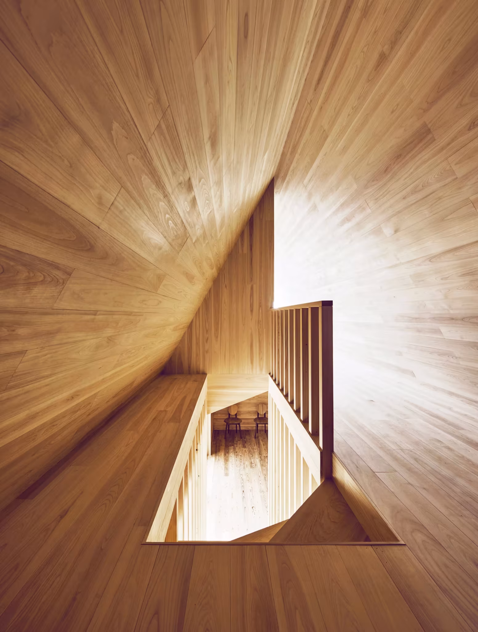 Hueco triangular entre superficies de cedro con una barandilla de madera en el interior de la Yoshino Cedar House