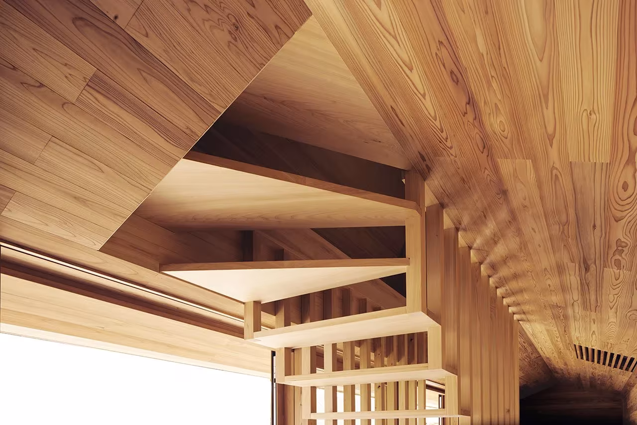 Techo de lamas de cedro y estructura de madera iluminada en el interior de la Yoshino Cedar House de Samara