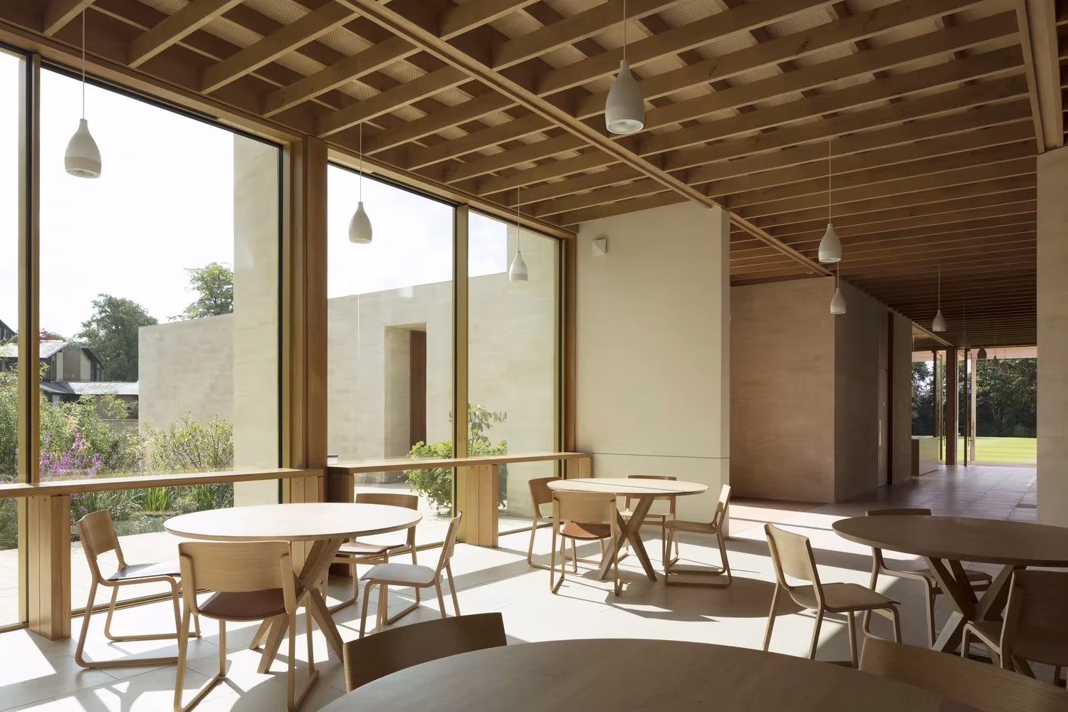 Comedor con mesas redondas bajo techo de casetones de madera y cristaleras al jardín en Worcester College, de McLaughlin