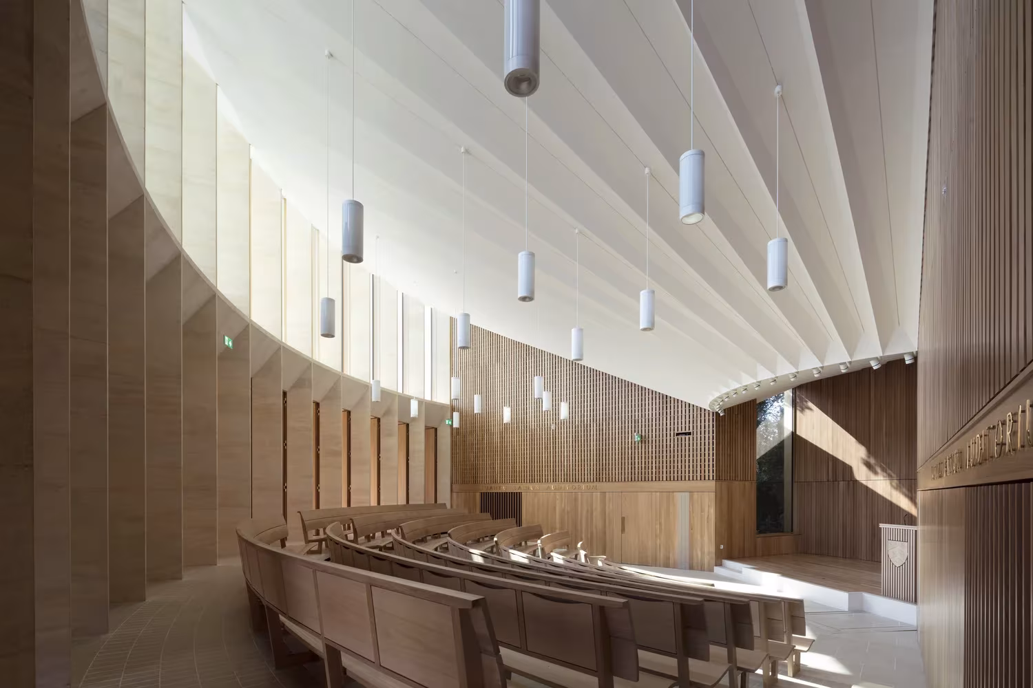 Sala curva con bancos de madera y techo plisado blanco en el auditorio del Worcester College de Oxford