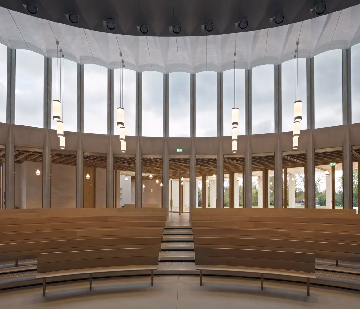 Sala circular con bancos escalonados de madera y vanos altos que rodean el auditorio del Worcester College