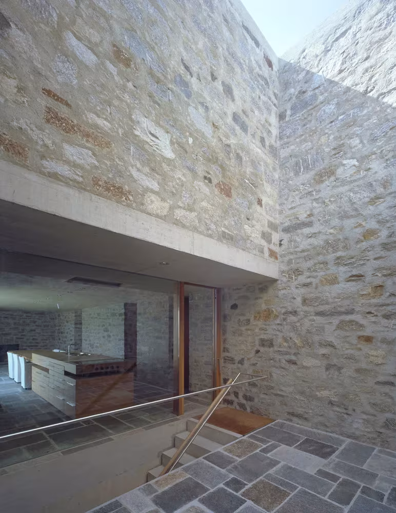 Patio de piedra con un vidrio que descubre la cocina en la Casa Brione, de Wespi de Meuron Romeo