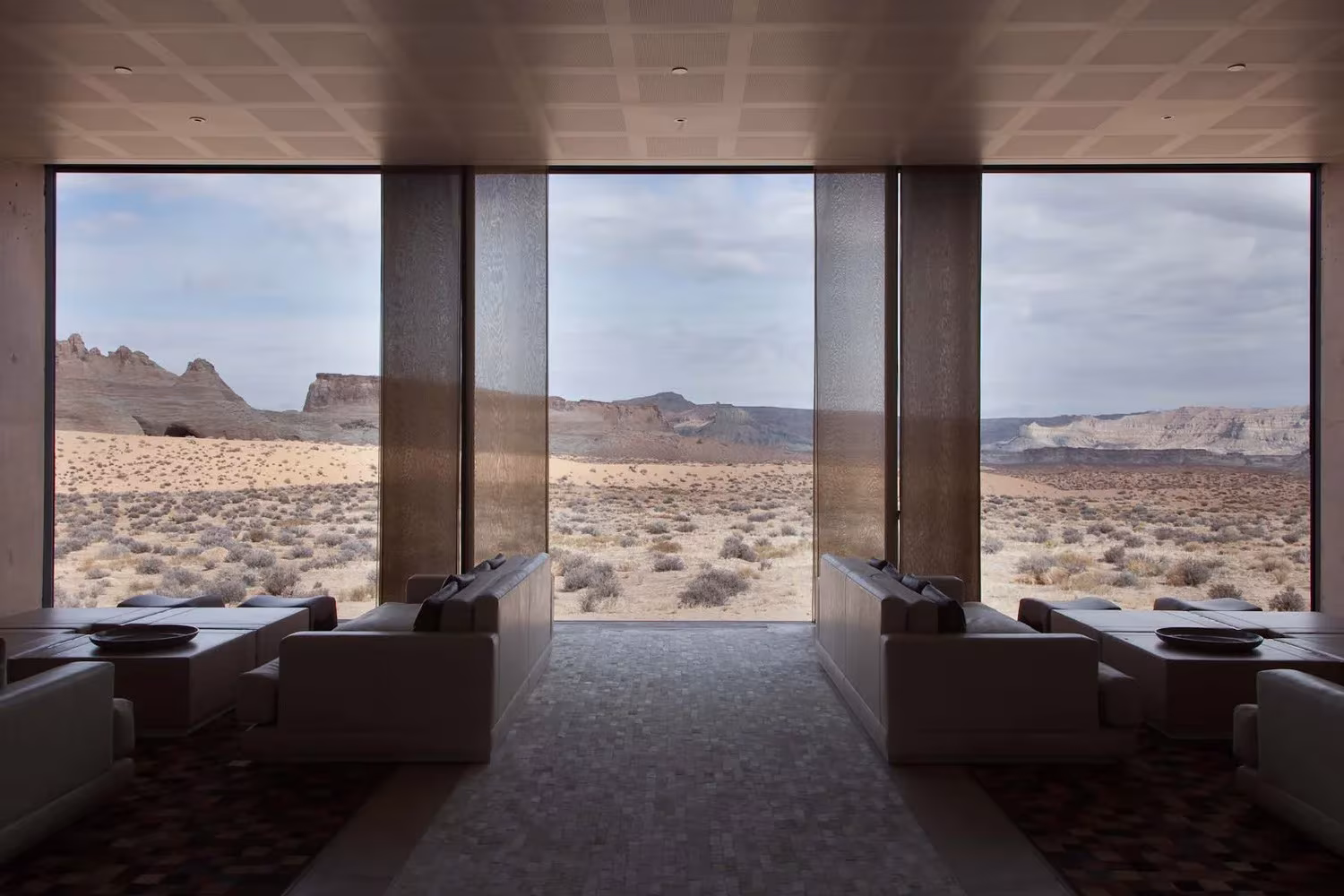 Salón del Amangiri con ventanal enmarcado en hormigón abierto al desierto de Utah