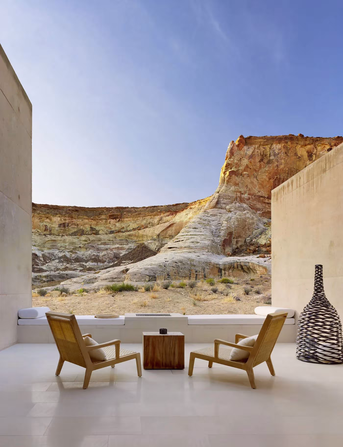 Estancia abierta del Amangiri con butacas de madera y vistas a una pared rocosa del desierto de Utah