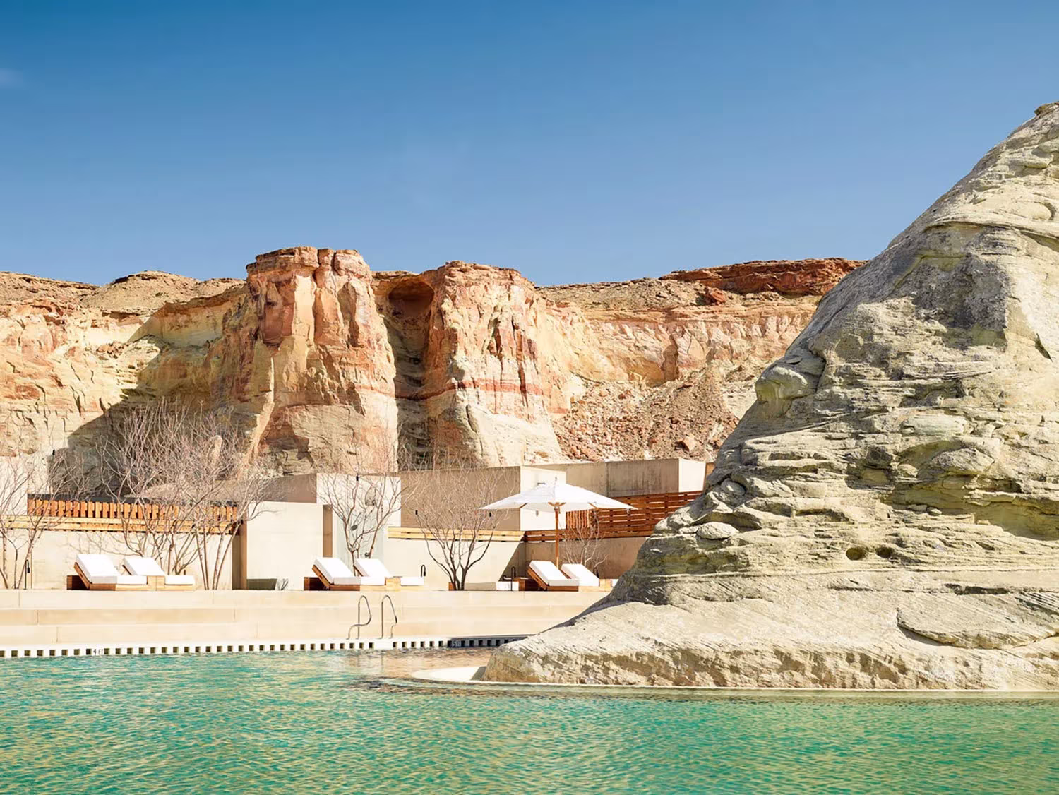 Piscina del Amangiri junto a un farallón de arenisca y tumbonas blancas en el desierto de Utah