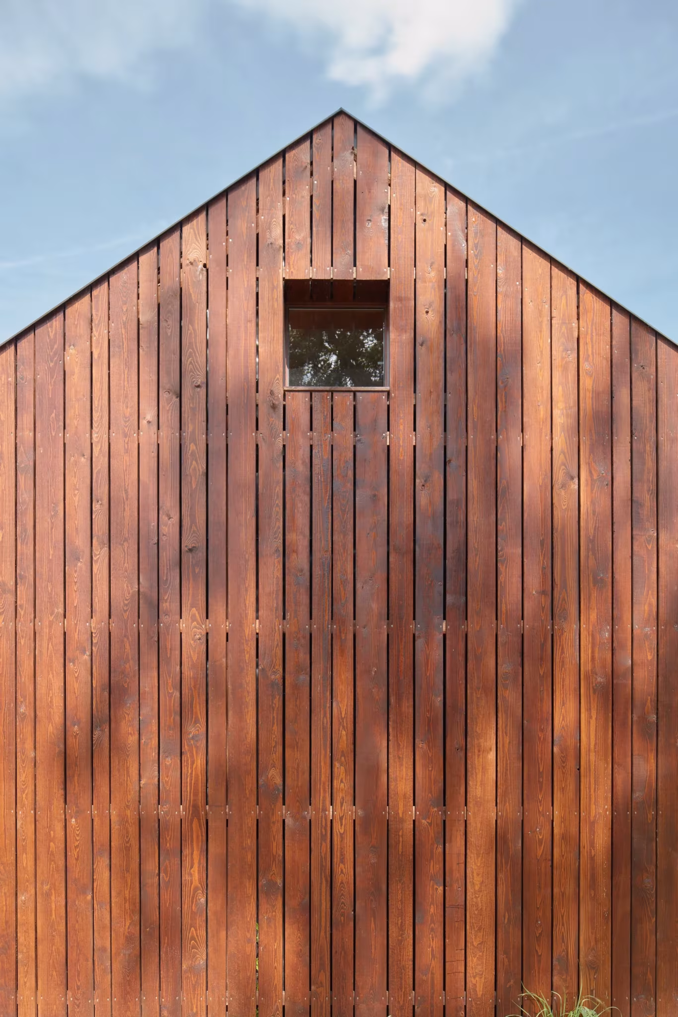 Testero de listones de madera con una pequeña ventana cuadrada en una cabaña de Atelier 111