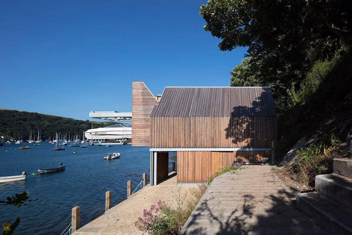 Berberis Boathouse de Wimshurst Pelleriti desde el camino de acceso, con la ría y los barcos al fondo