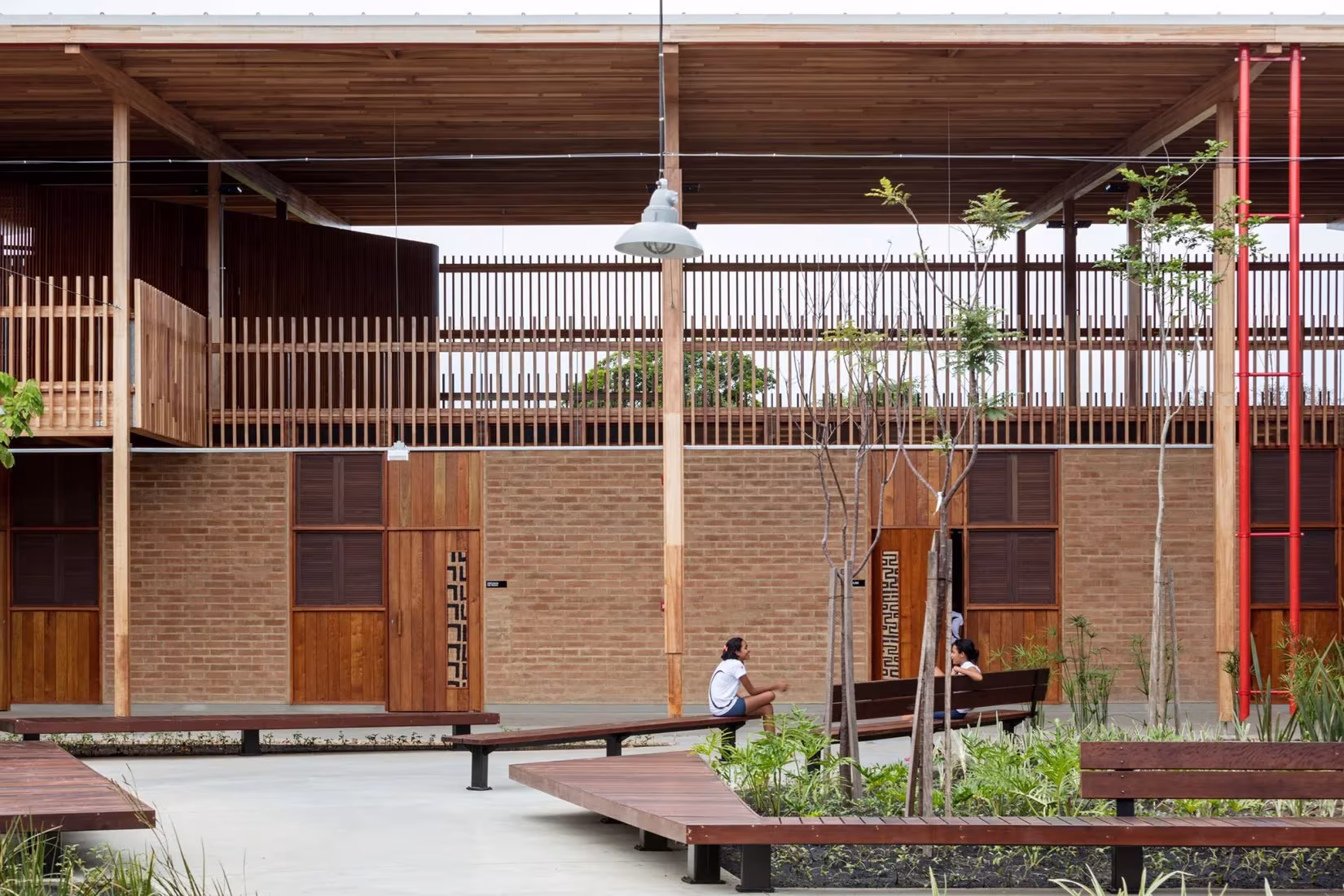 Patio de la escuela de Canuanã con muros de ladrillo, galería de madera y bancos de madera entre plantas