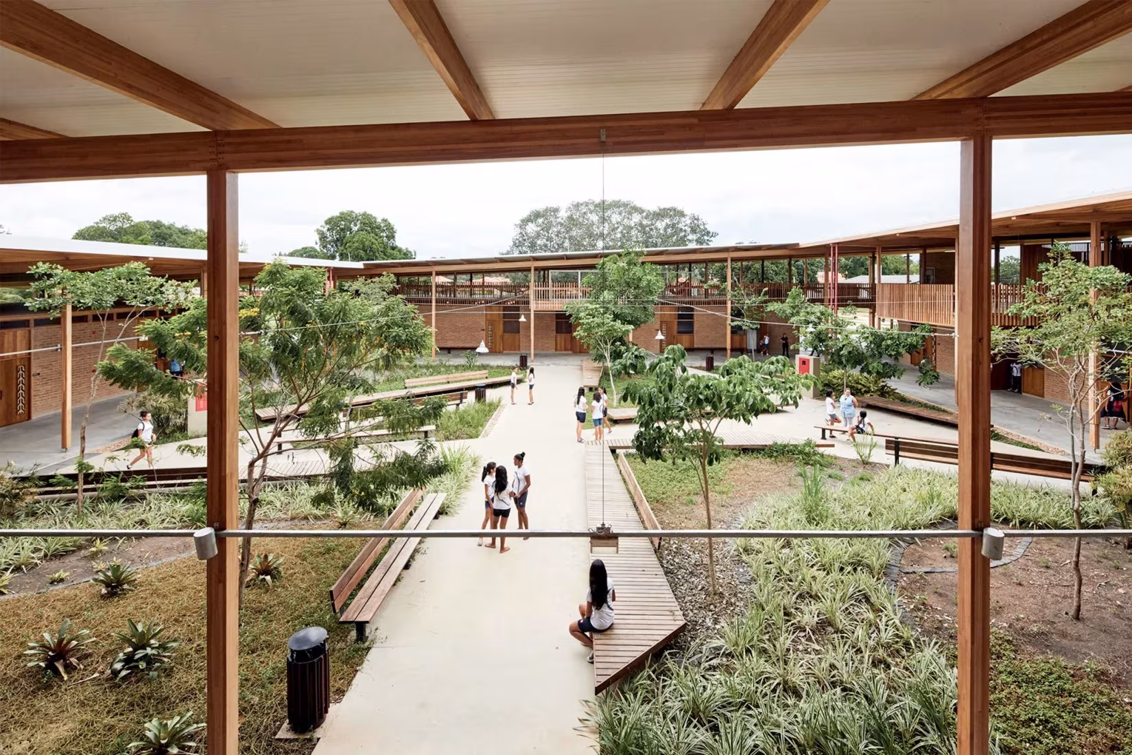 Patio ajardinado de la Ciudad de los niños visto desde la galería de madera, con paseo y bancos
