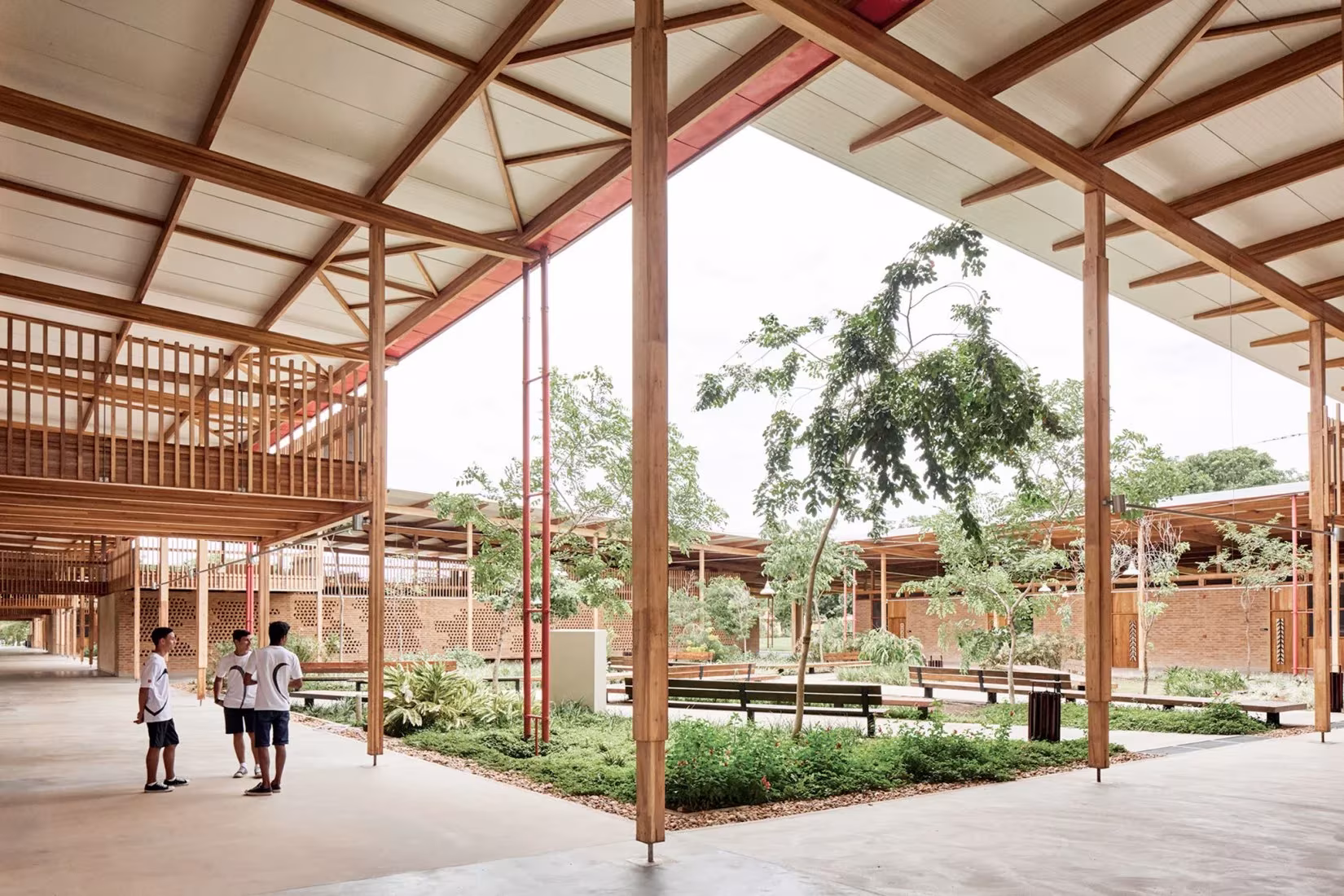 Patio ajardinado de la Ciudad de los niños de Rosenbaum y Aleph Zero entre galerías de pilares de madera