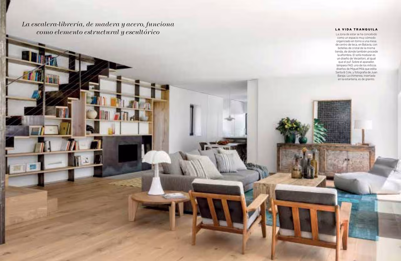 Salón con librería de madera y acero junto a la escalera en el reportaje Campo Libre de Nuevo Estilo