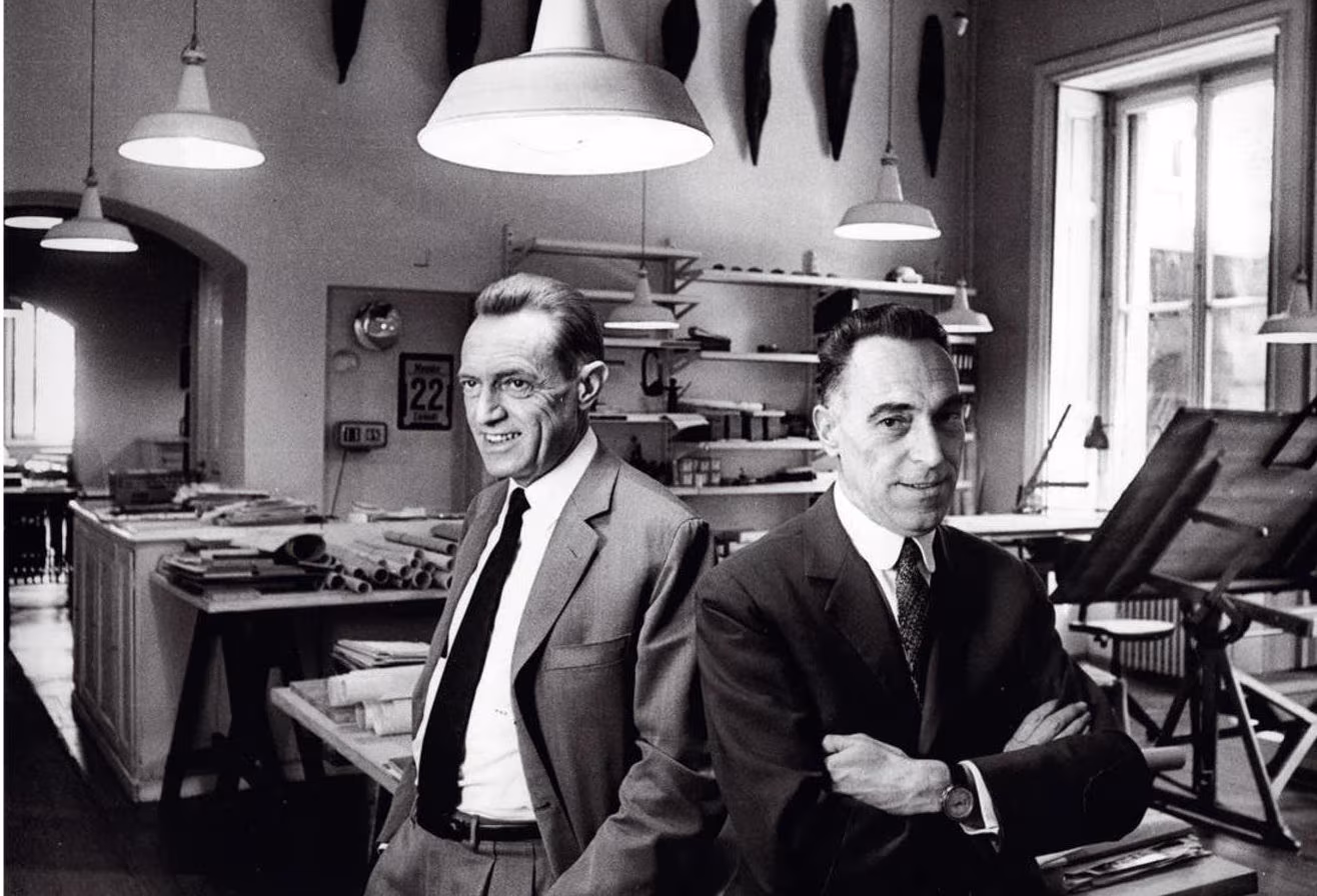 Fotografía en blanco y negro de los hermanos Castiglioni con los brazos cruzados en su estudio de diseño