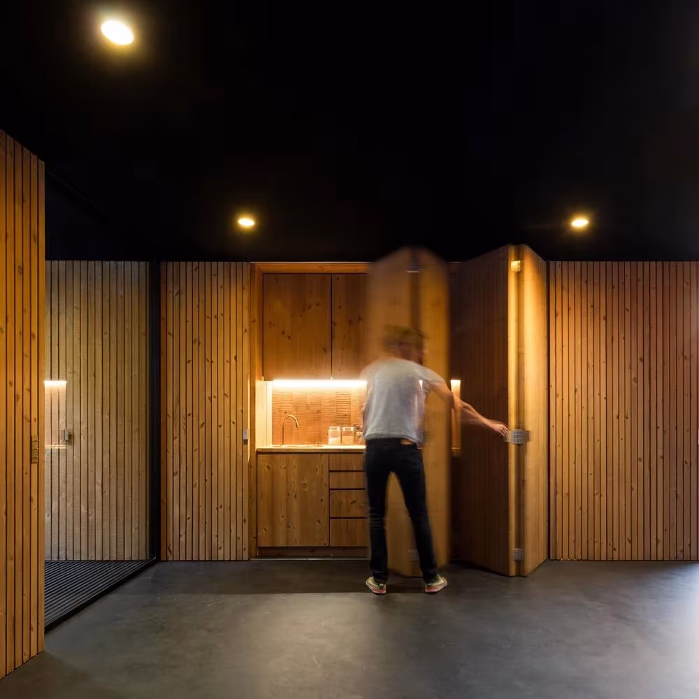 Armario-cocina de madera abierto como una puerta pivotante en el interior de la casa-pabellón de Guimarães