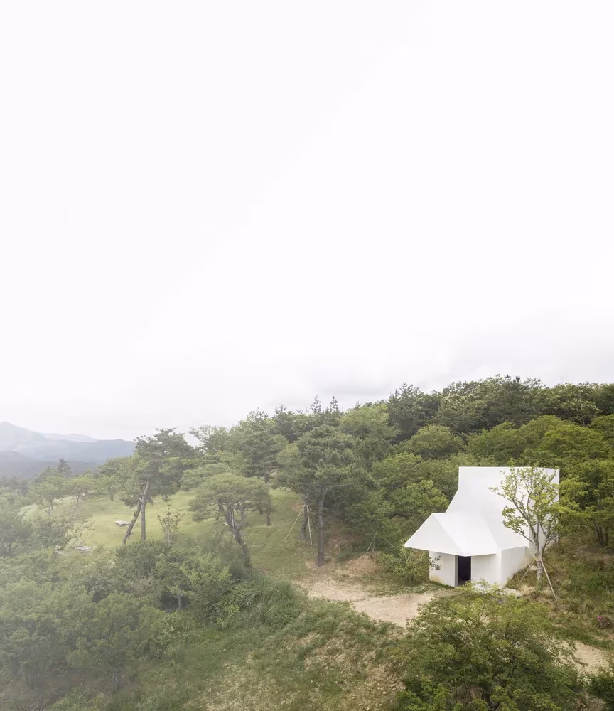 Casa blanca de cubierta quebrada sobre una colina boscosa y brumosa en Saya Park, Corea del Sur