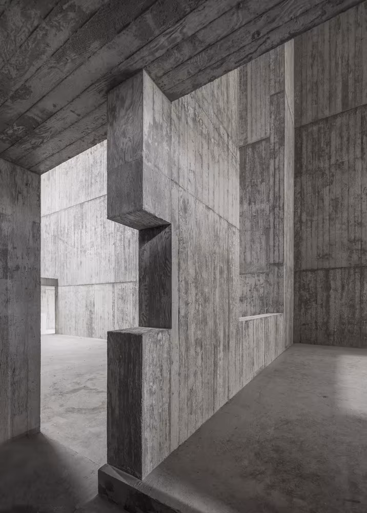 Interior de hormigón visto con muros recortados y ventana alta en el pabellón de Siza en Saya Park