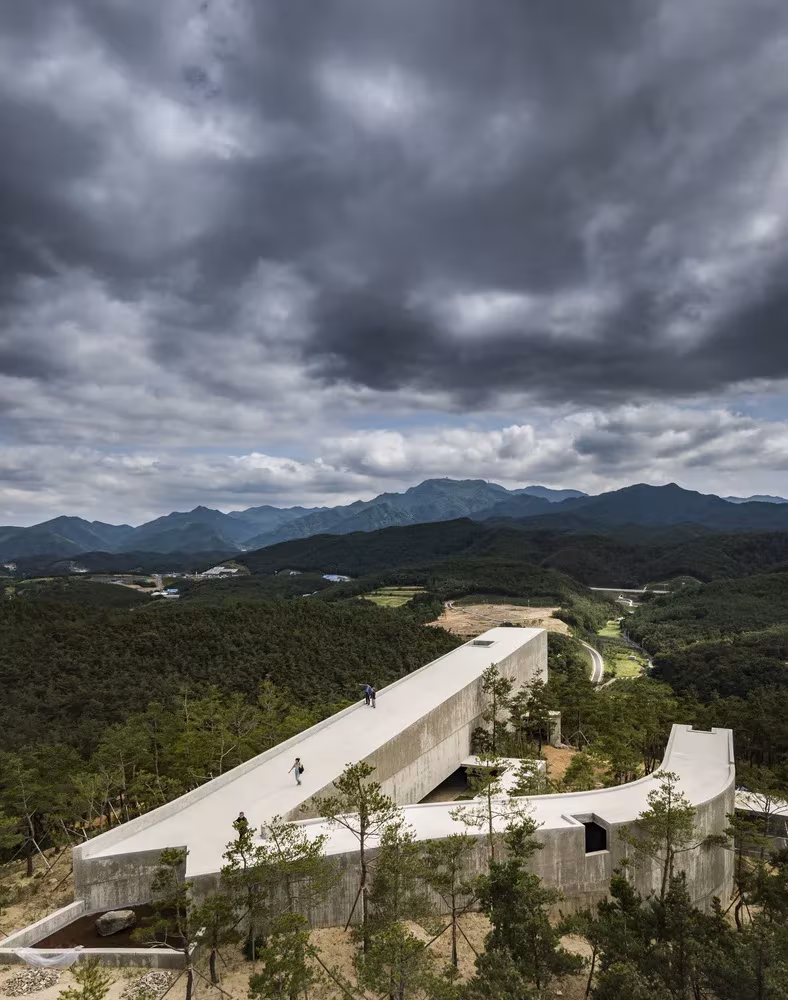 Cubierta transitable de hormigón del pabellón de Álvaro Siza sobre el bosque, con las montañas al fondo, Corea
