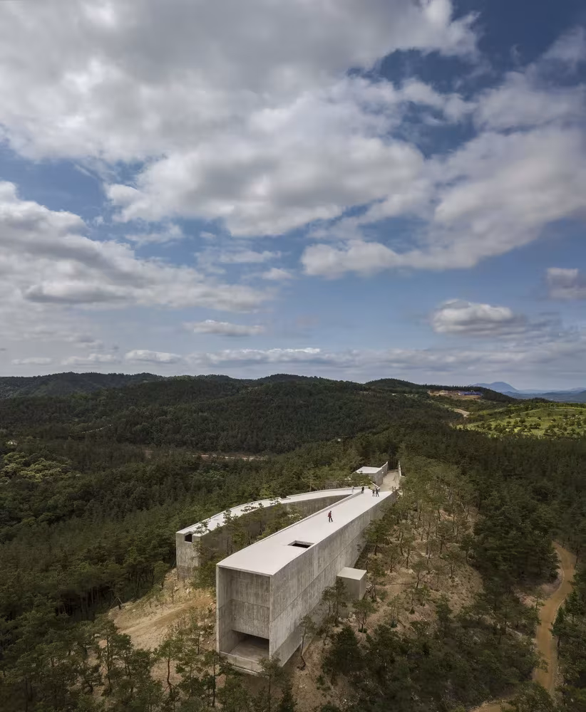 Pabellón de hormigón de Siza y Carlos Castanheira en Saya Park, serpenteando sobre la cresta boscosa
