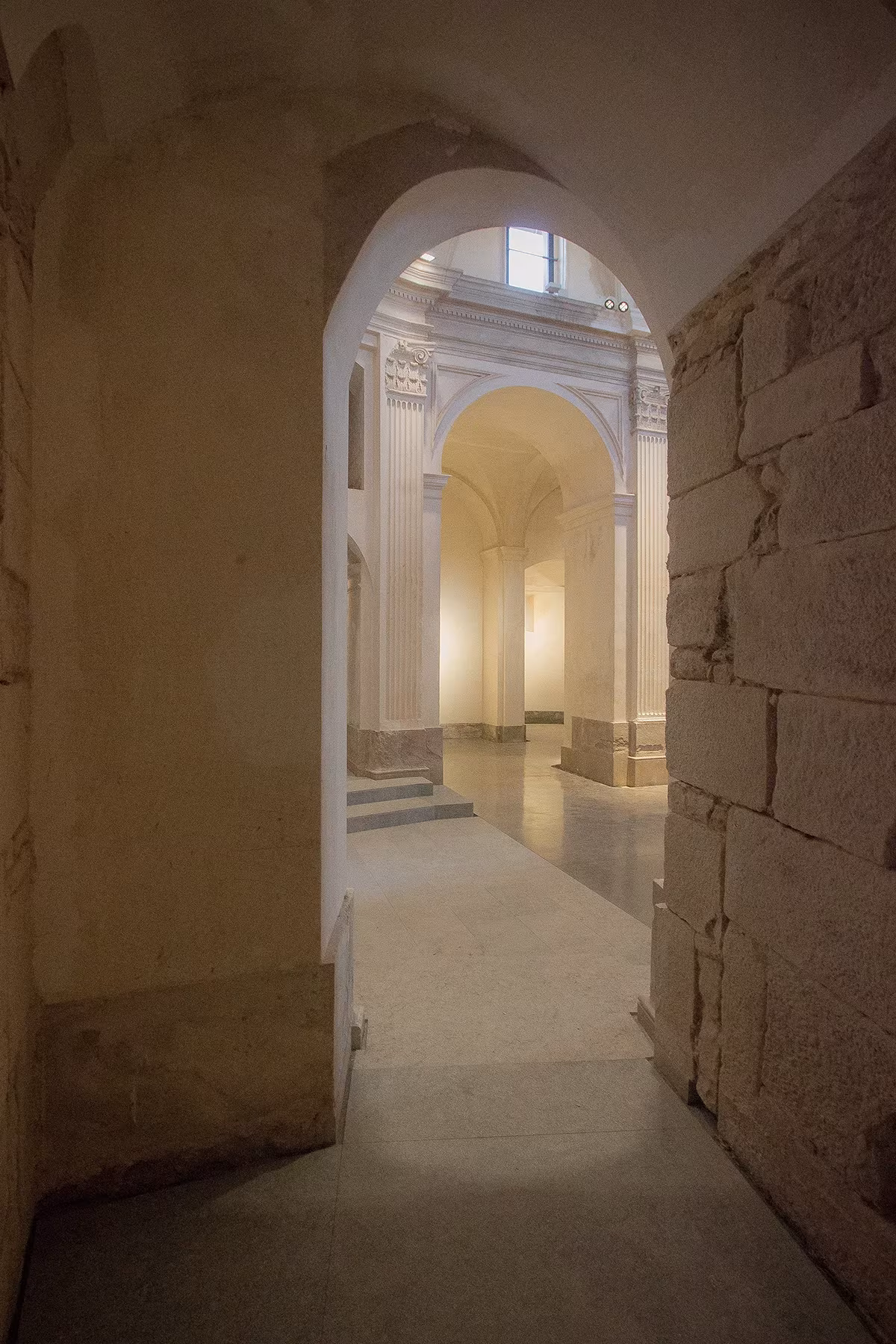Pasillo de piedra que se abre a una sala abovedada y luminosa en la iglesia de Sant Sadurní de Callús