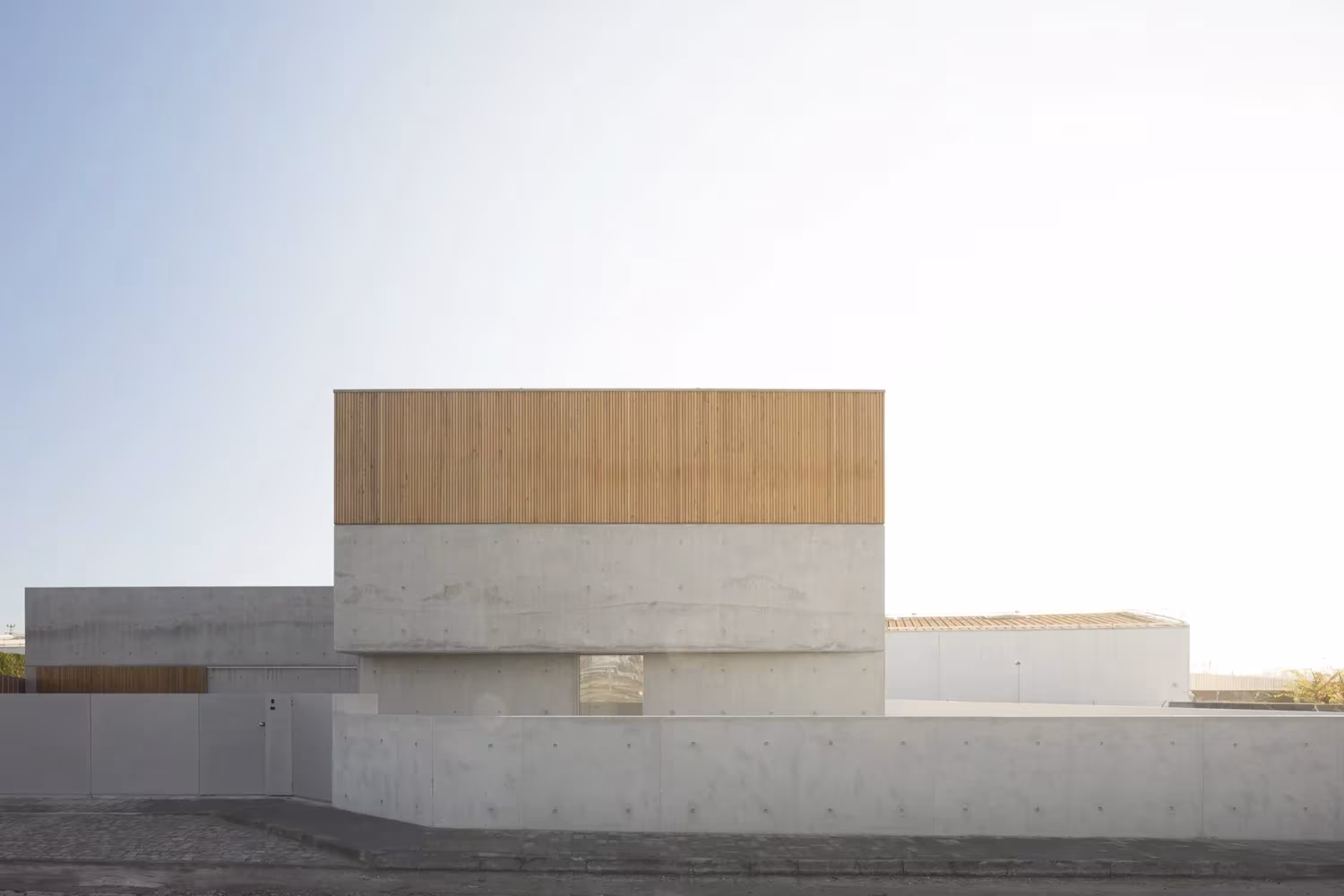 Casa en Avanca de nu.ma en tono claro, con el volumen de madera superpuesto a los cuerpos de hormigón
