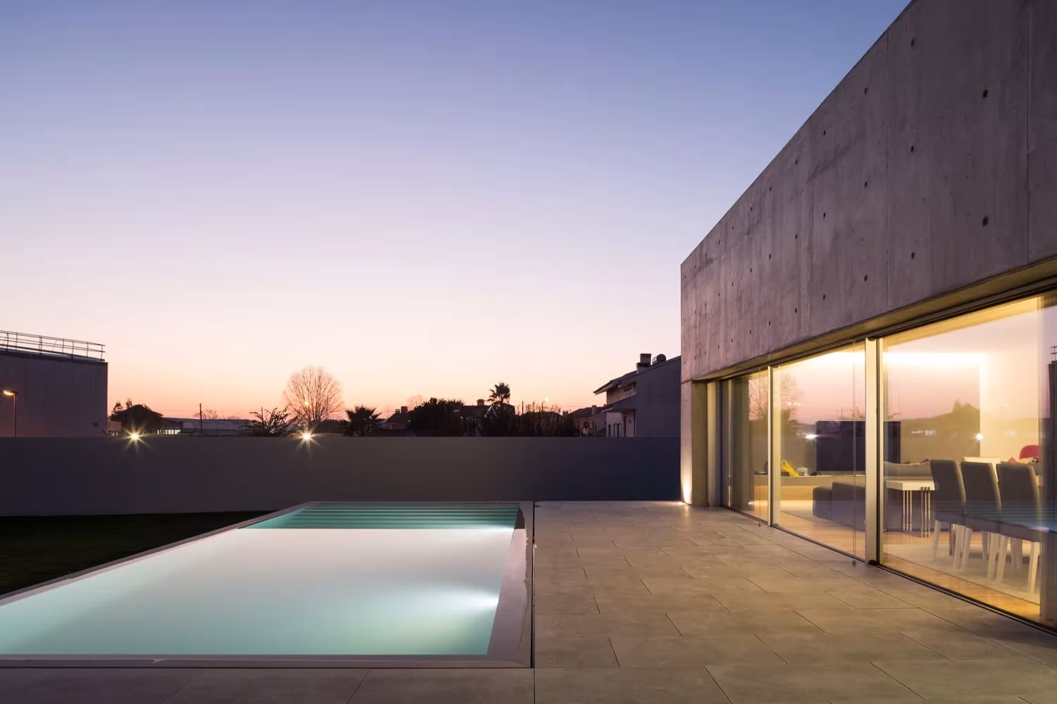 Piscina y salón iluminados al atardecer tras los ventanales de la Casa en Avanca, junto a Oporto