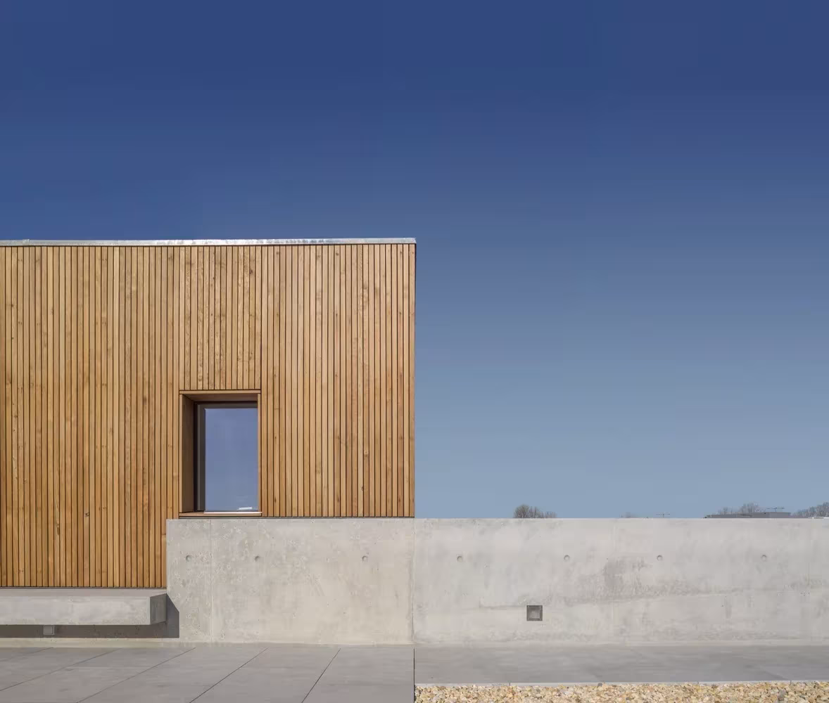 Volumen de lamas de madera con ventana cuadrada sobre el muro de hormigón de la Casa en Avanca