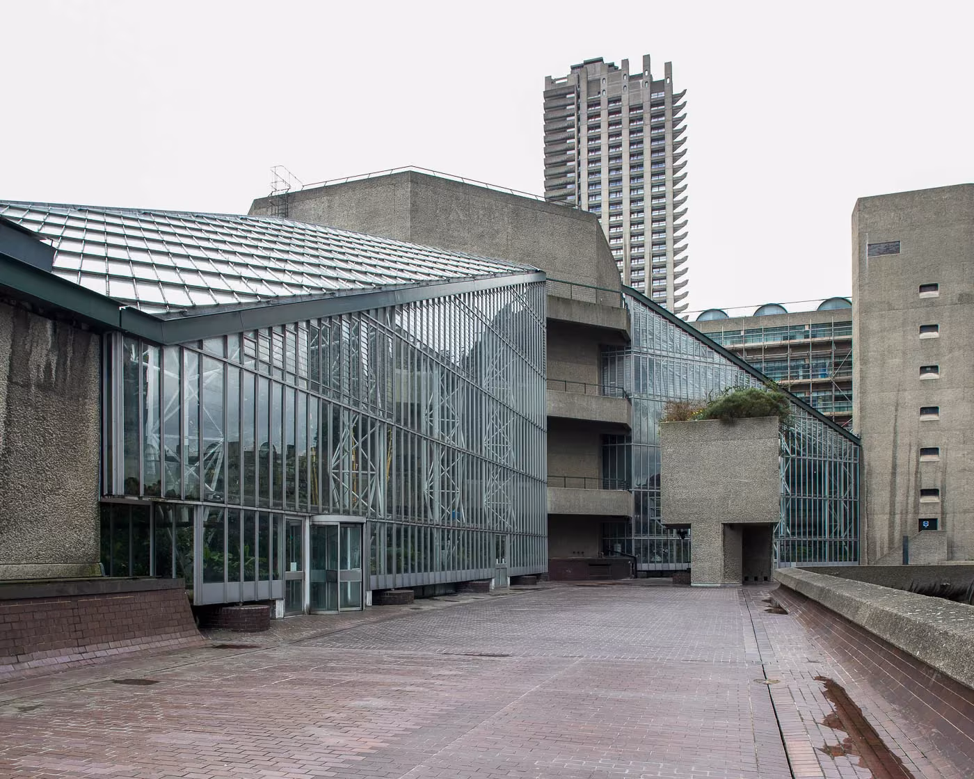 Fachada acristalada del Barbican Conservatory junto a los edificios de hormigón y la torre residencial, Londres