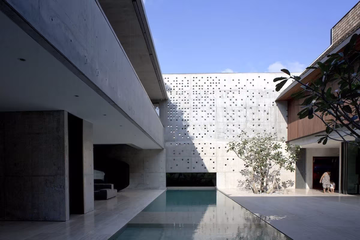 Piscina alargada del patio de la Courtyard House de Formwerkz Architects, junto al muro calado de hormigón