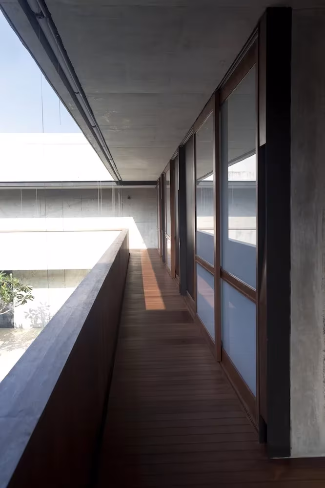 Corredor de madera con cerramiento acristalado junto al borde del patio en la Courtyard House de Singapur